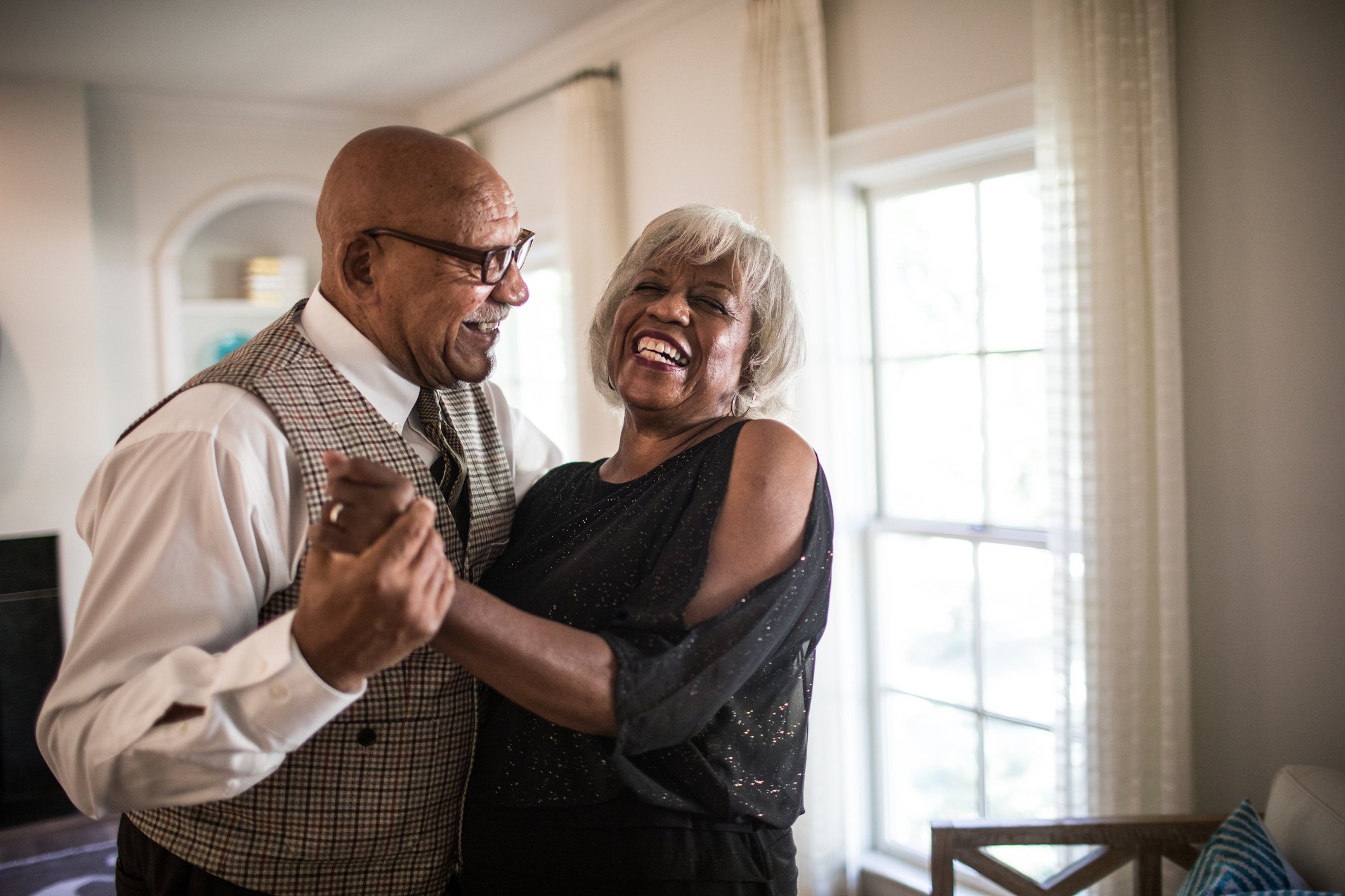 A retired couple dances happily at home.