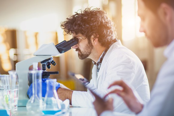A researcher looks through a microscope in a lab.