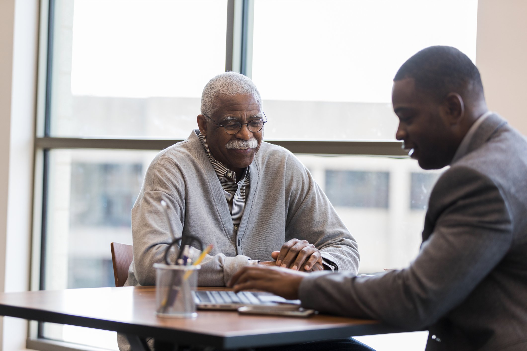 Two people sitting at a table looking at a laptop.