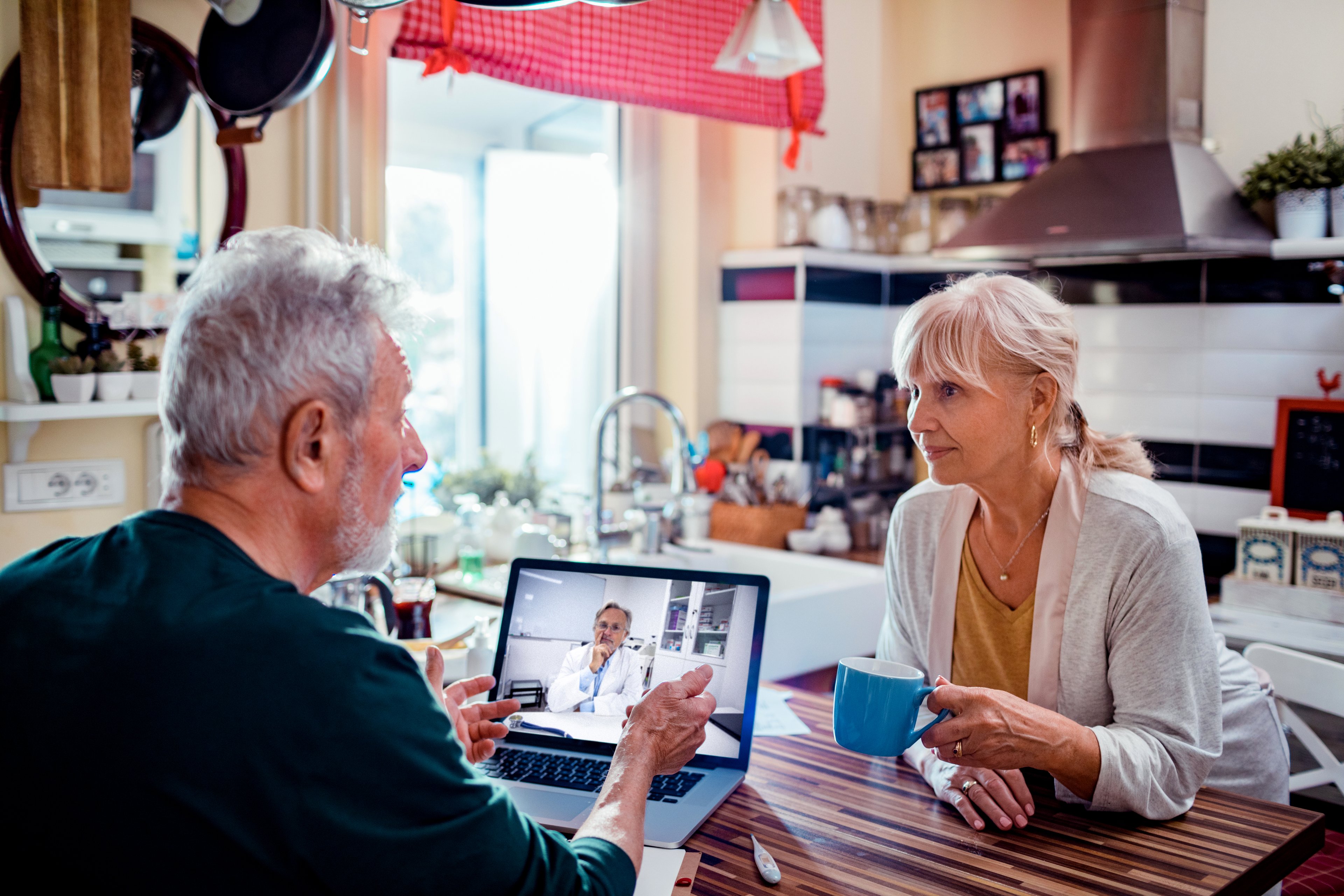 Couple on virtual doctor's appointment in kitchen.