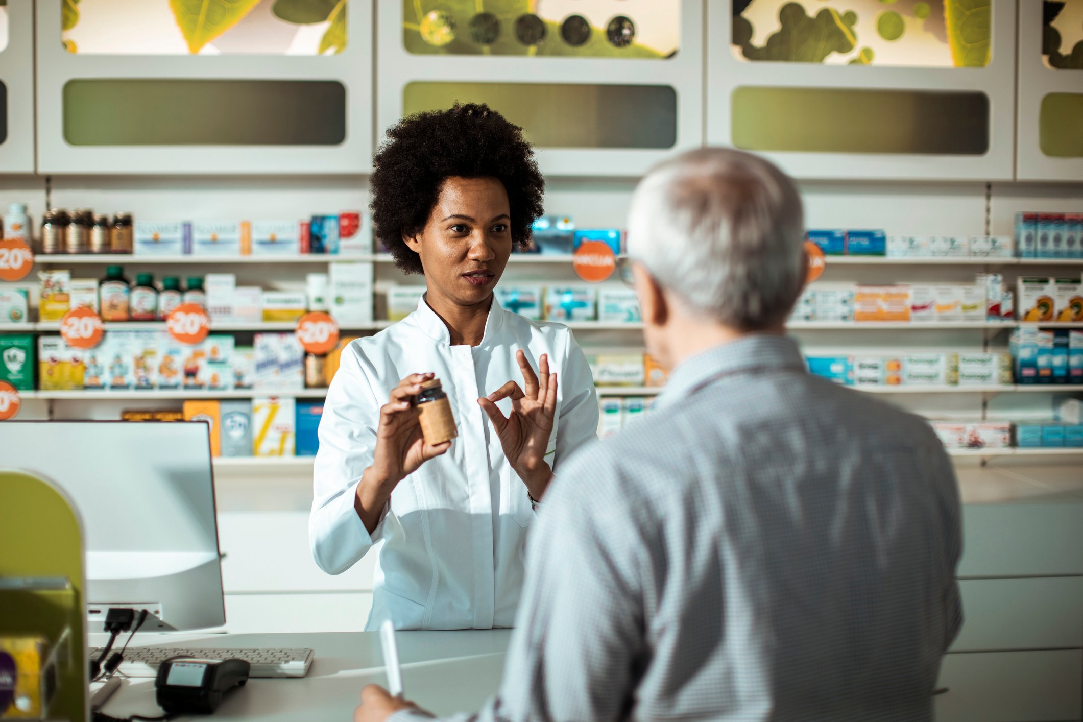 A pharmacist helps a customer at the counter.