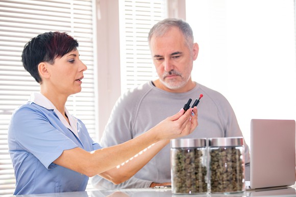 Clerk at a cannabis dispensary showing cannabis oil options to a customer.