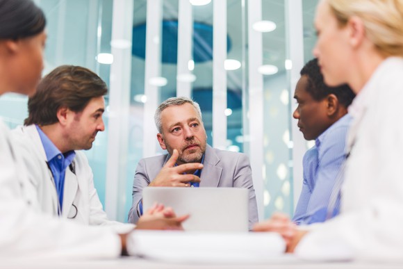 A group of business people discuss something in a conference room.