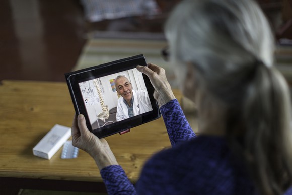 A patient holds a mobile tablet while conducting a virtual care visit.
