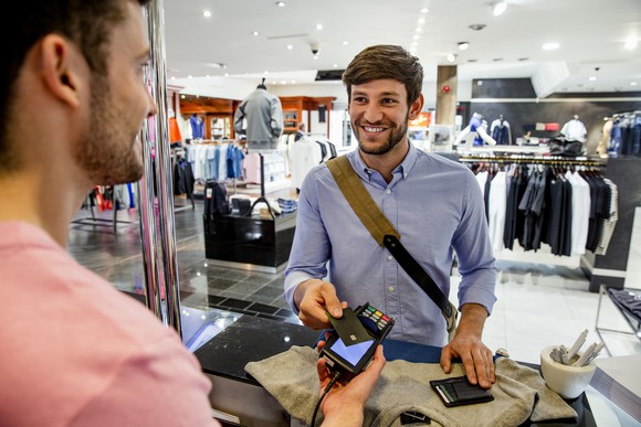 Person paying with credit card in a clothing store. 