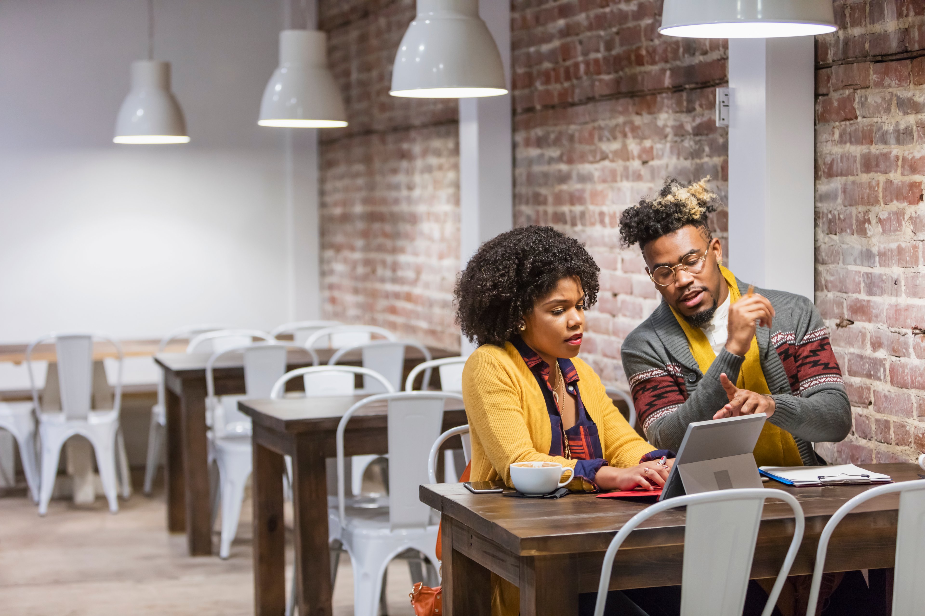 A young man and woman sitting at a table at a coffee shop.