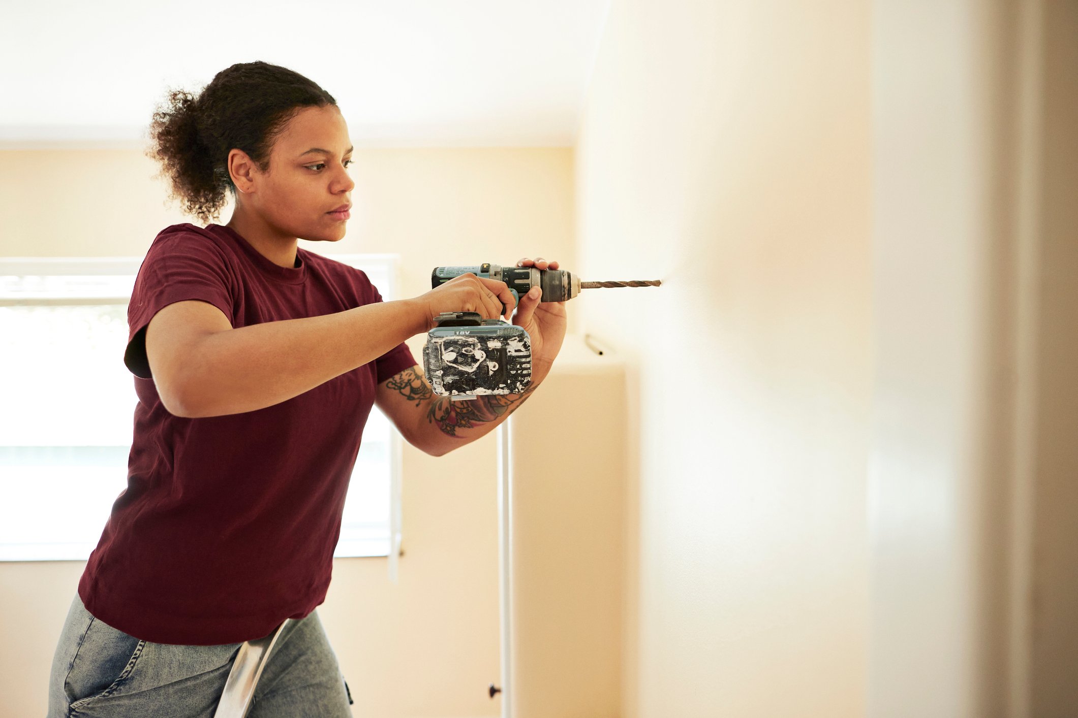 A person drilling into a wall while renovating a room.