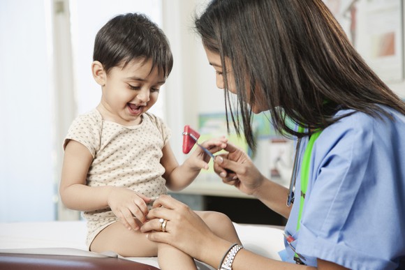 Child smiling having reflexes checked.