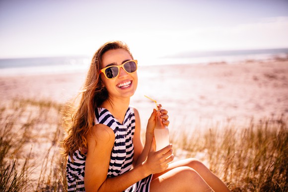 Person enjoying a sparkling drink in the sun.
