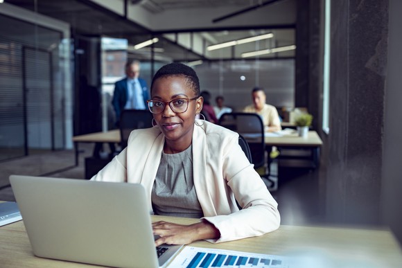 A worker uses a laptop inside of an office.