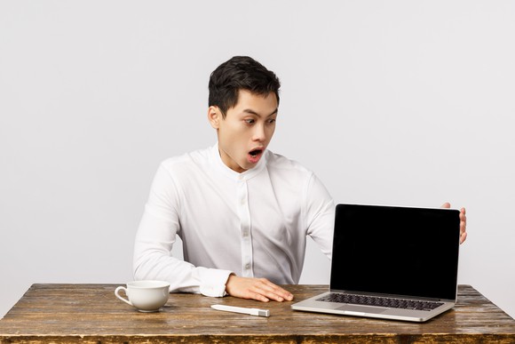 A person with their jaw agape while looking at a laptop computer.