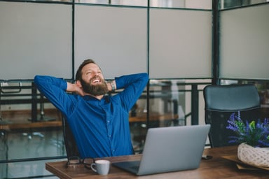 A man smiles while working on a laptop.