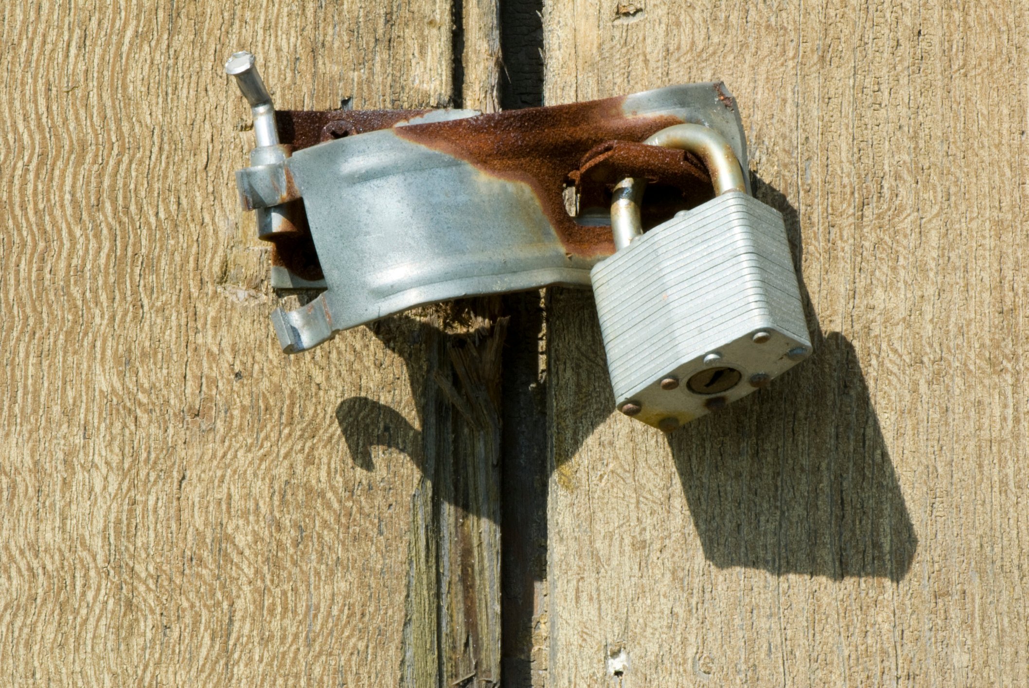 A broken door latch hanging on a door.