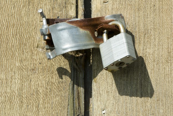 A broken door latch hanging on a door.