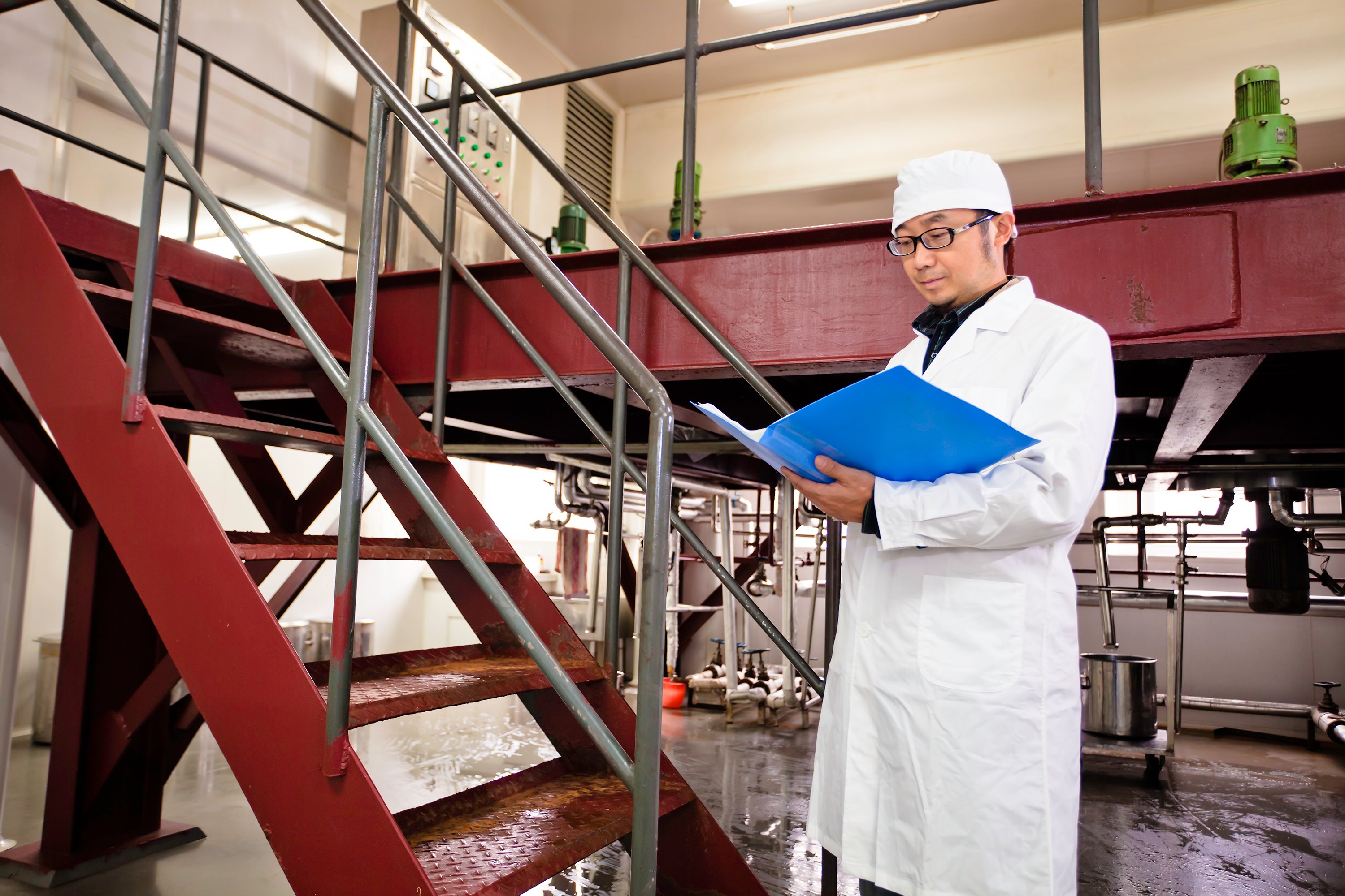 An inspector at a production facility takes notes.