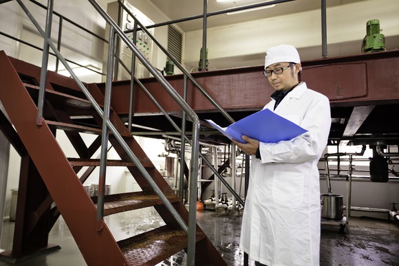 An inspector at a production facility takes notes.