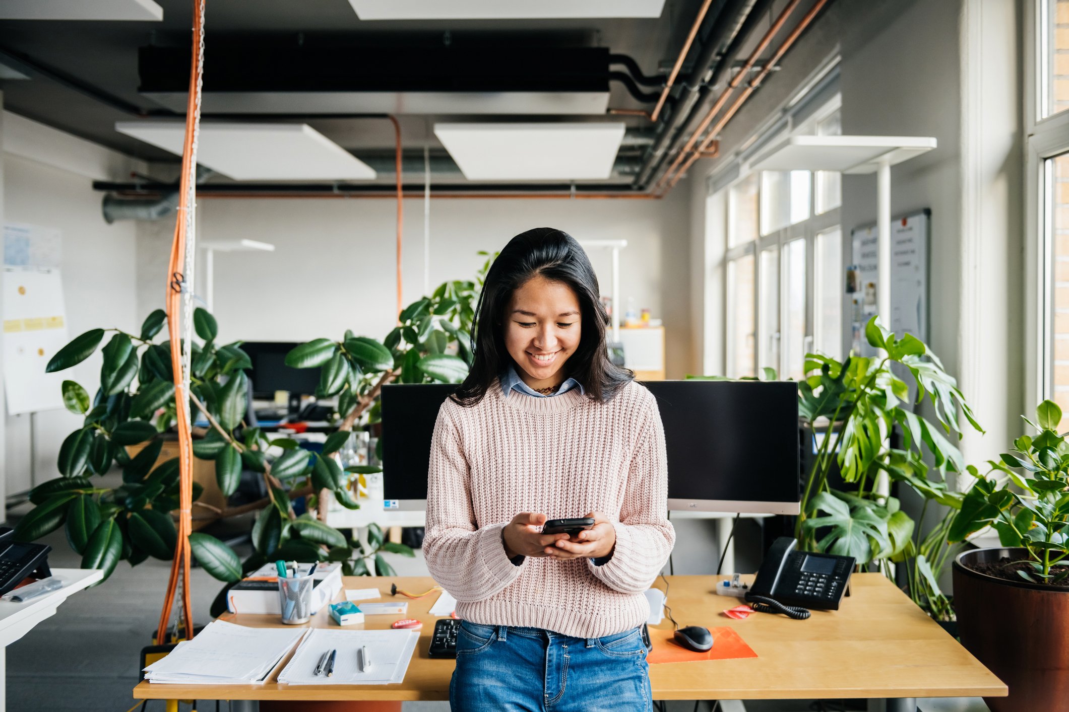 A person standing while using a phone in an office.