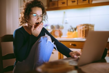 A person looking shockingly at a laptop screen.
