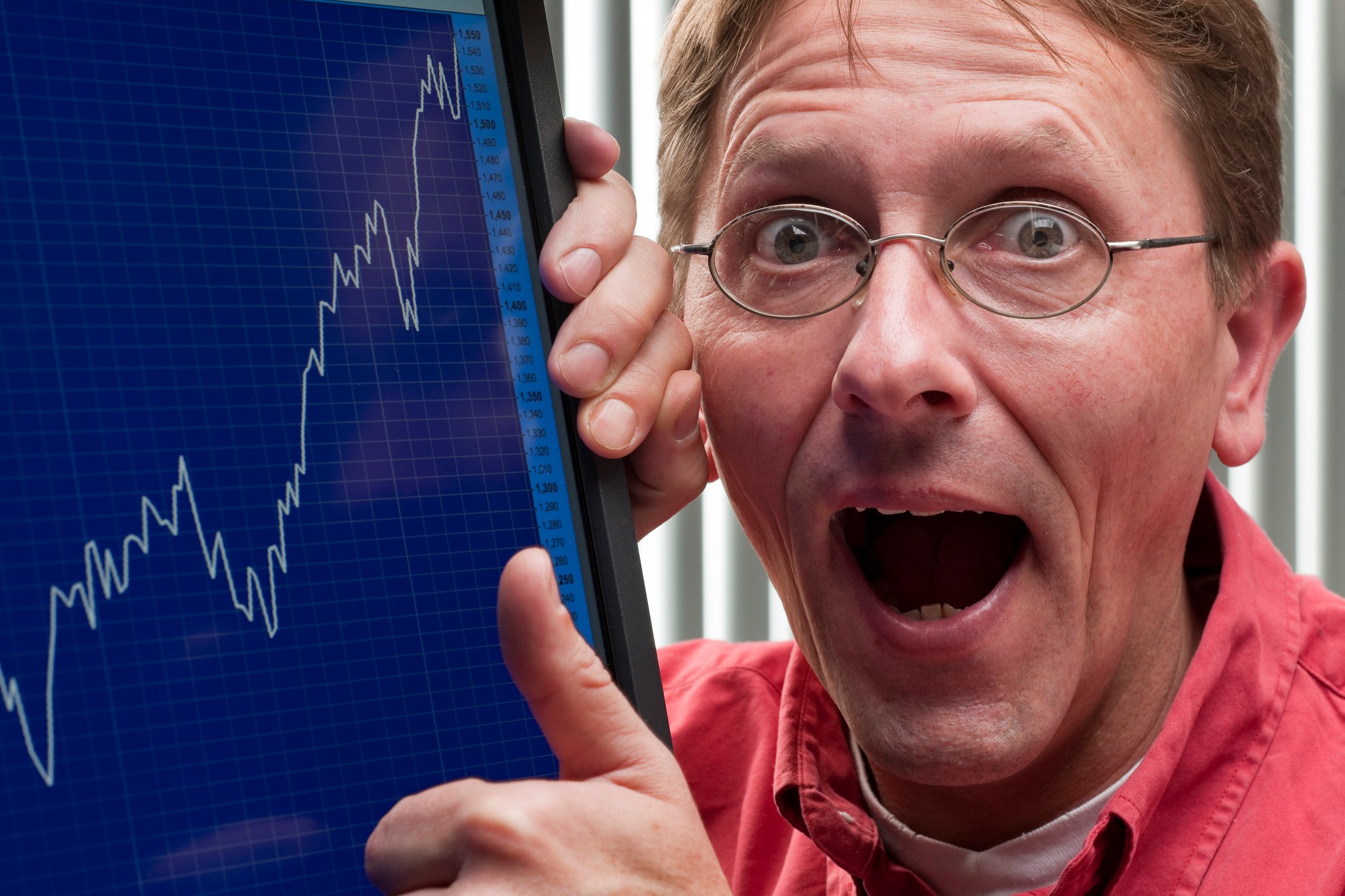 Person with mouth open in shock pointing to a positive stock chart.