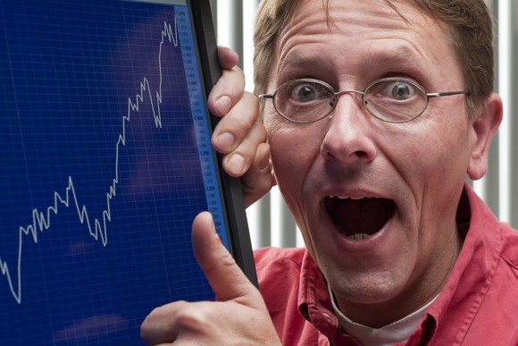 Person with mouth open in shock pointing to a positive stock chart.