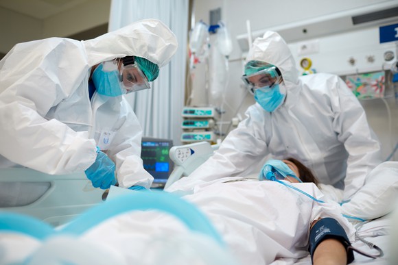 Masked and gloved doctors work on a patient.