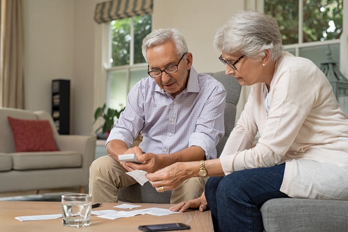 Two older adults sitting together reviewing paperwork.