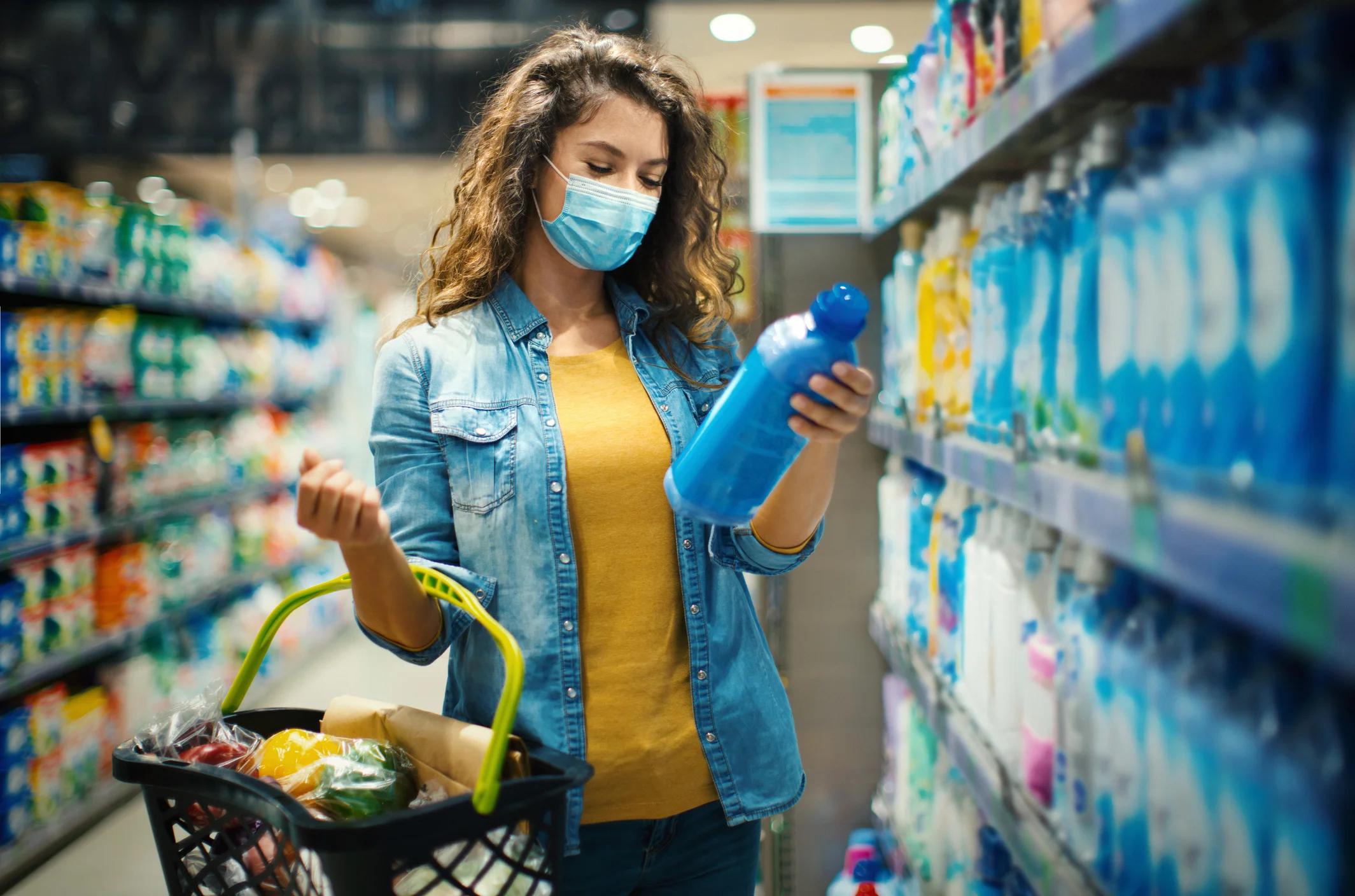 Person in store aisle looking at a bottle of dishwashing soap.