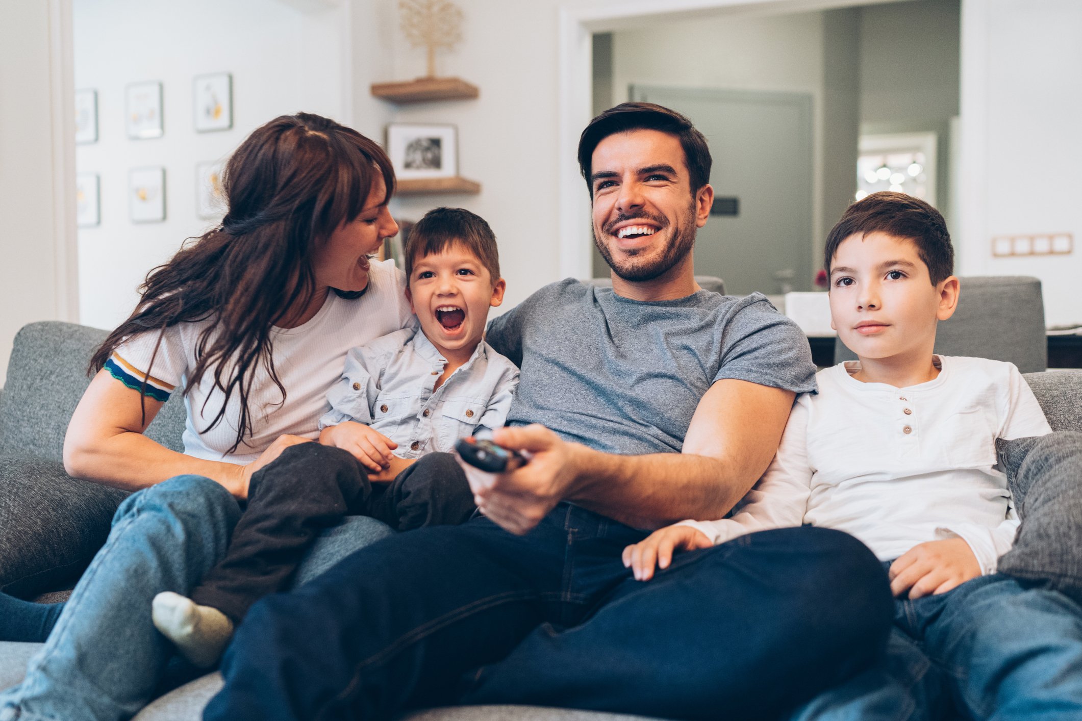 A smiling family of four watching tv together.
