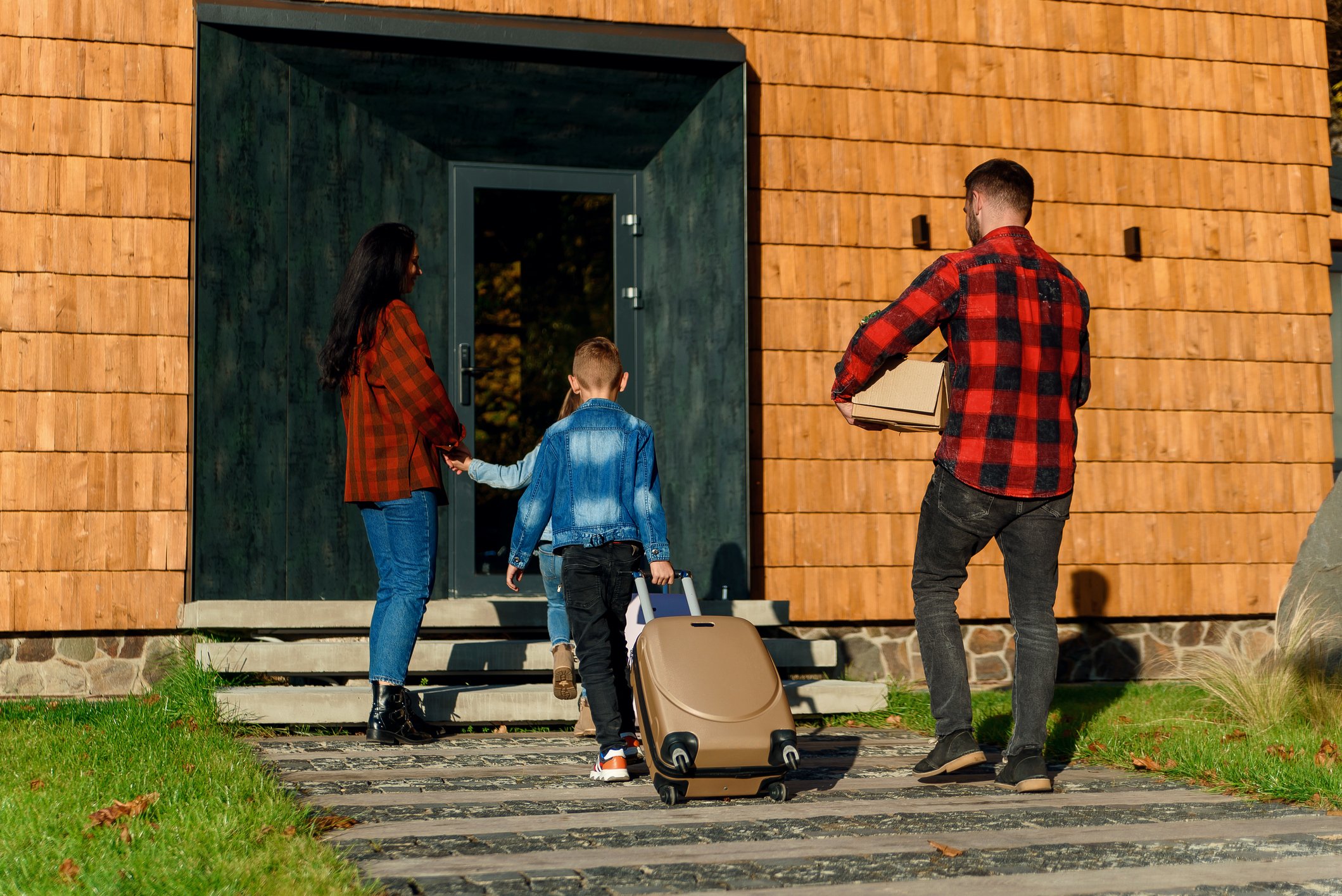 A family walking into a house with their luggage.