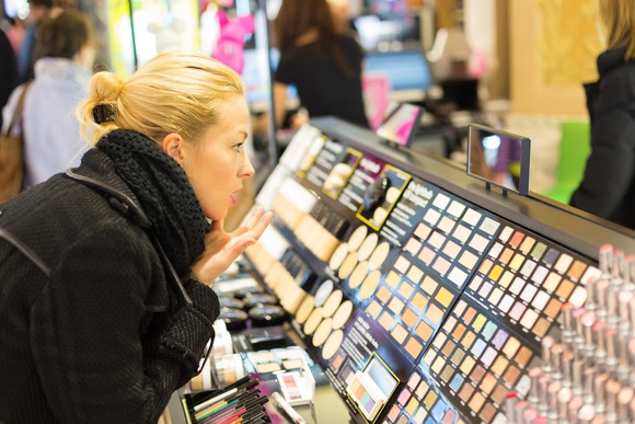 Person trying on cosmetics at a store counter.
