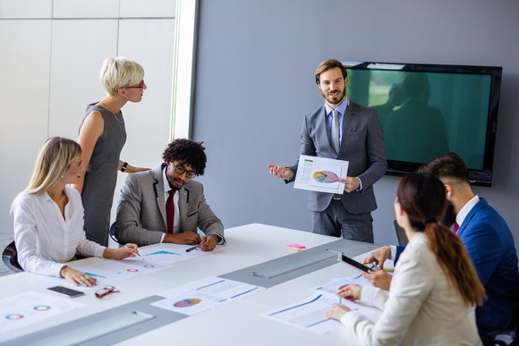 A businessperson gives a presentation to co-workers in a conference room.