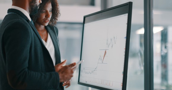 Two people looking at a stock chart.