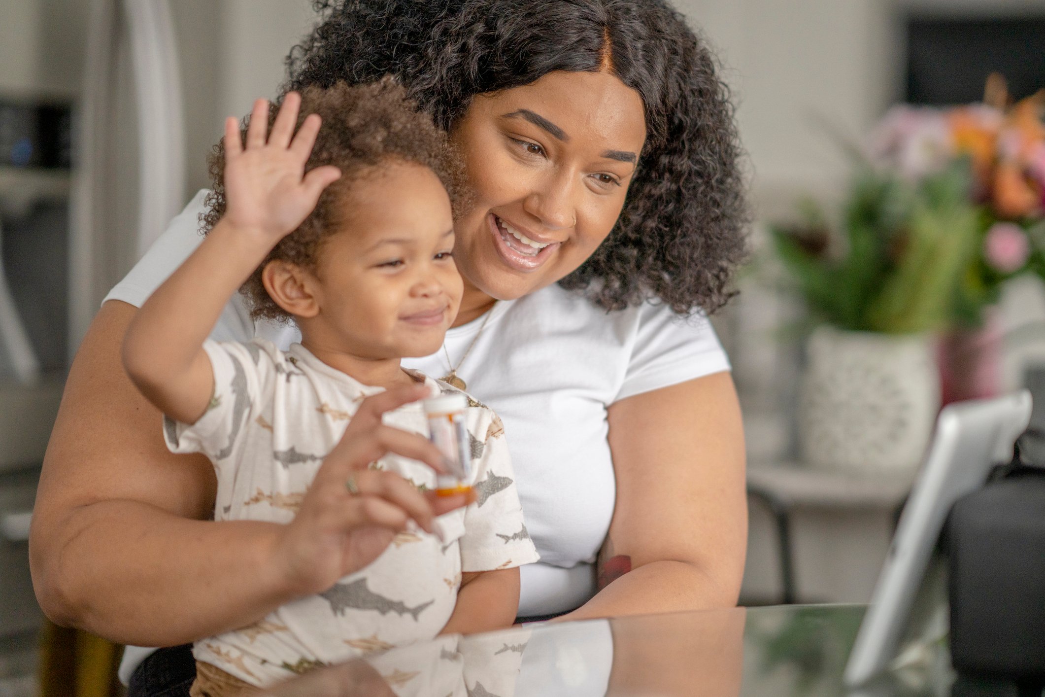An adult and a child sit in front of a tablet as they take part in an online medical visit. 
