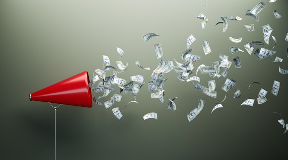 A flurry of hundred-dollar bills blowing out of a red megaphone.