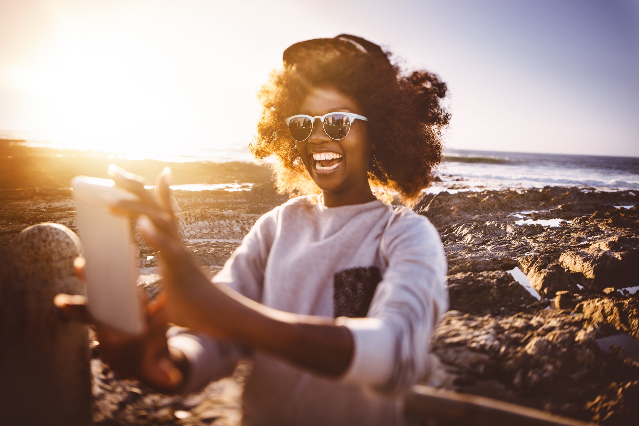 A smartphone user takes a selfie by the sea.