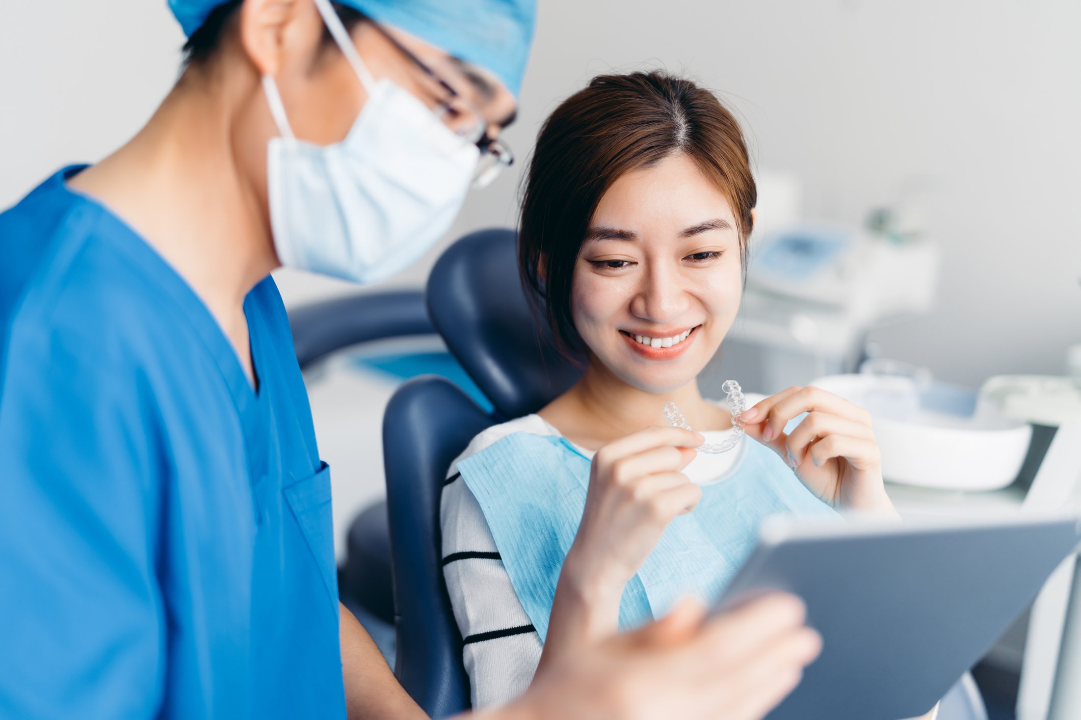 Patient holding clear aligner while getting a consultation from a professional. 