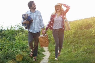 couple works together to carry a picnic basket