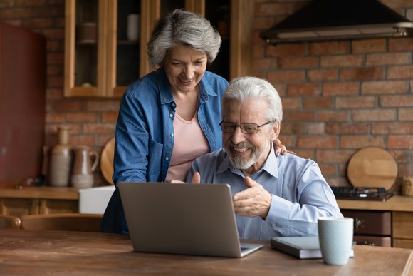 Two smiling people looking at a laptop.