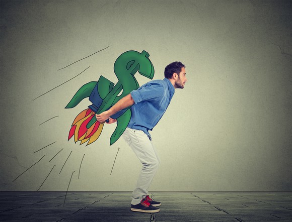 A person holding on to a money sign designed rocket.