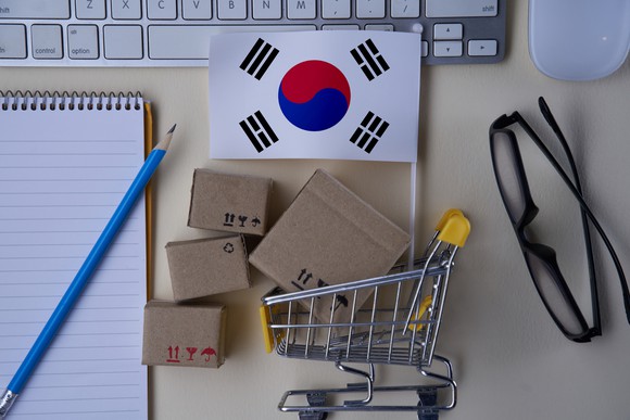 A South Korean flag with a tiny shopping cart on a desk.