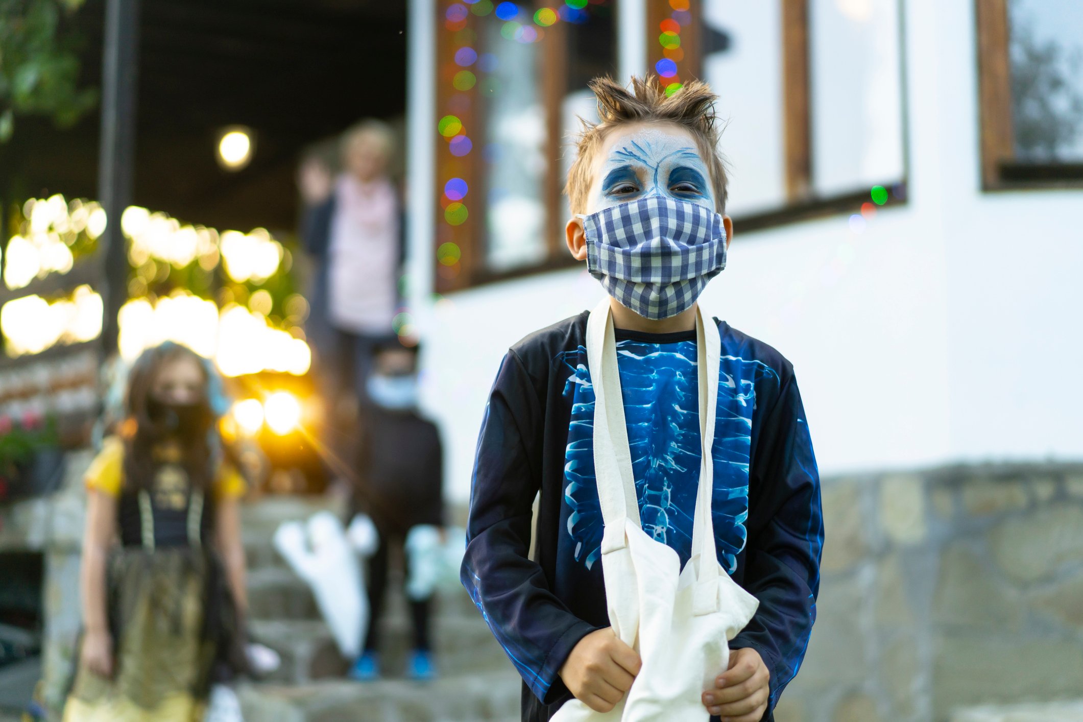 A child trick-or-treating while wearing a face covering.