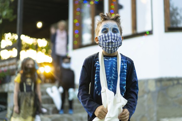 A child trick-or-treating while wearing a face covering.