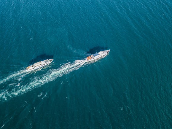 Two cruise ships move in the water with one in the lead.