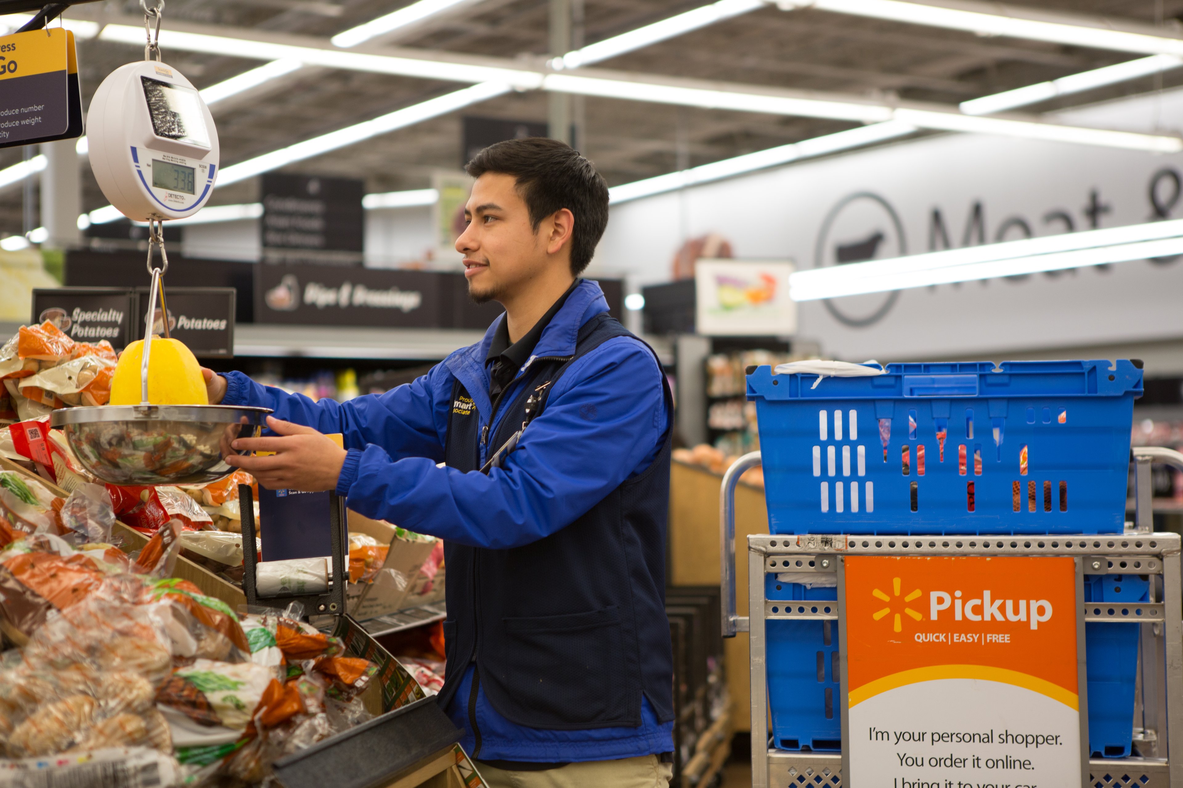 A Walmart employee weighs produce for placement on a pickup cart and eventual delivery to a waiting customer vehicle