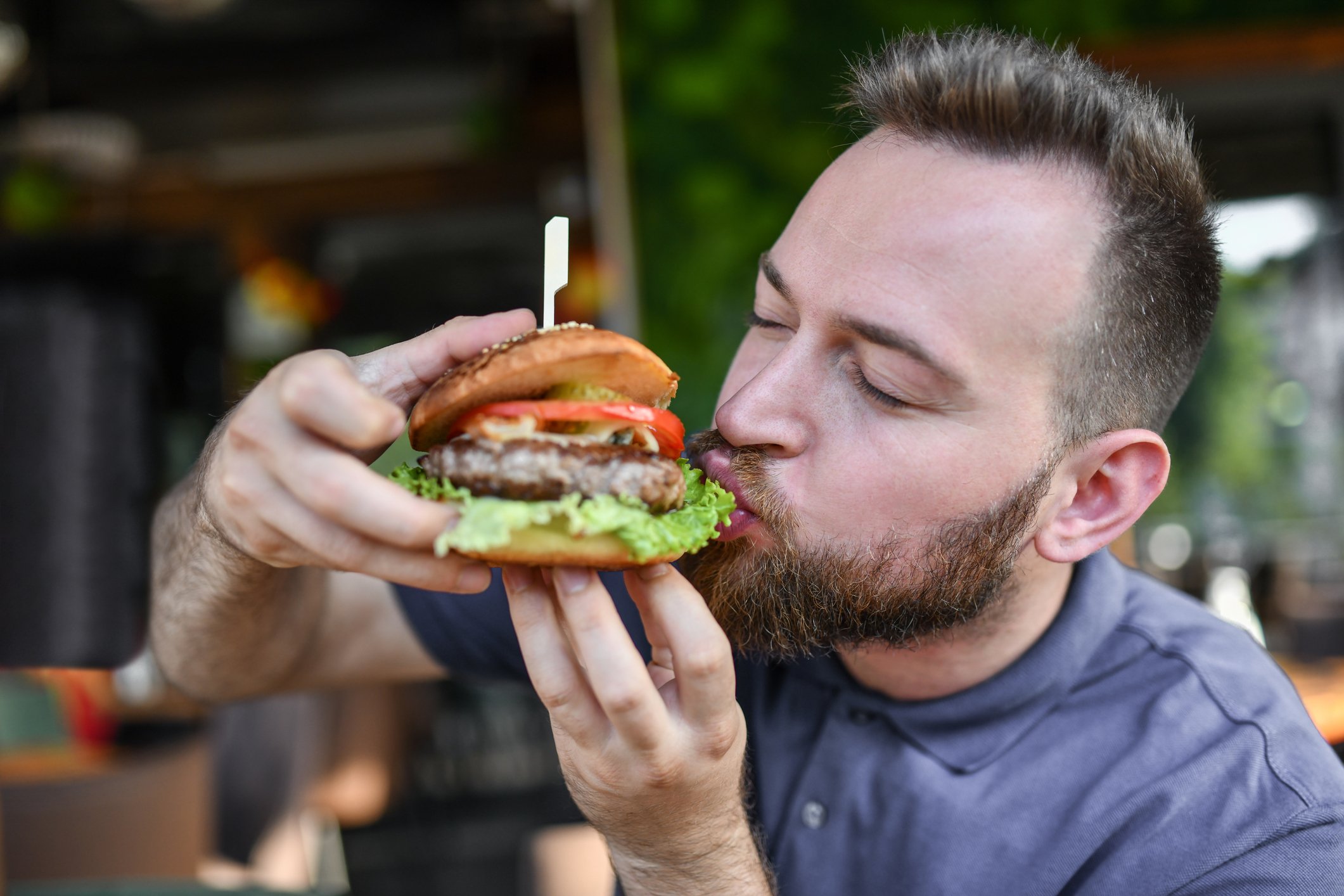 A man eats a veggie burger in an outdoor setting.