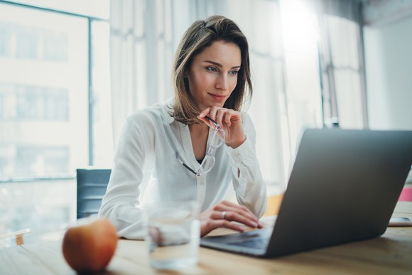 Person at a desk looking at something on a laptop.
