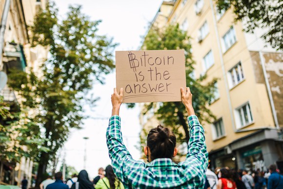 Person holding sign that says Bitcoin is the answer.