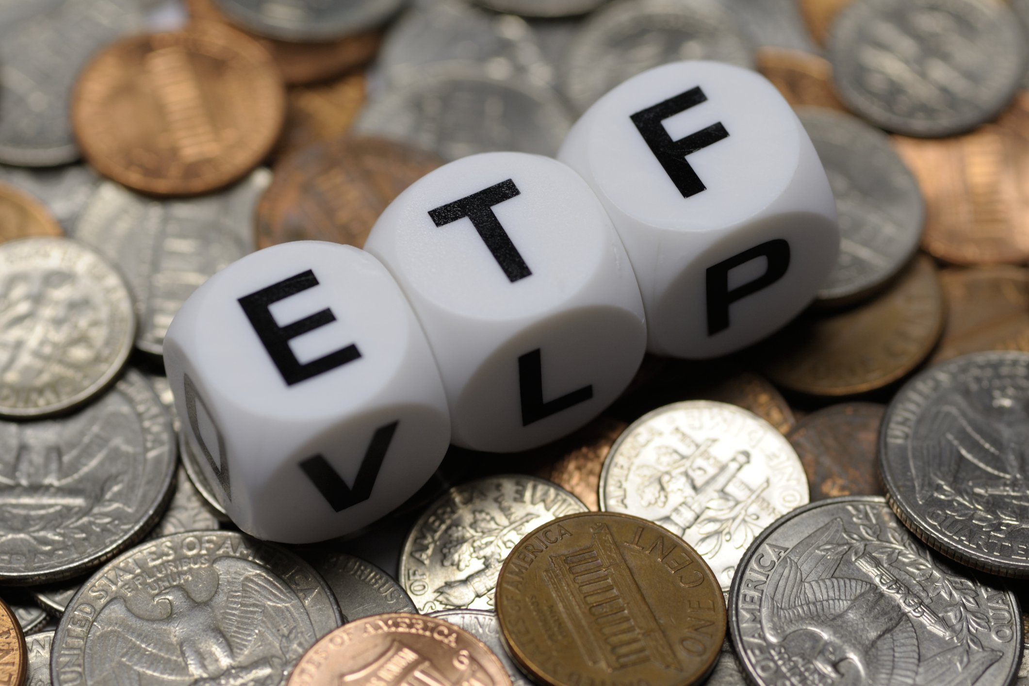 The letters ETF on tiles sitting atop loose change.