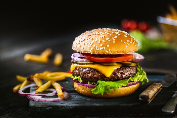 A burger and fries on a cutting board.