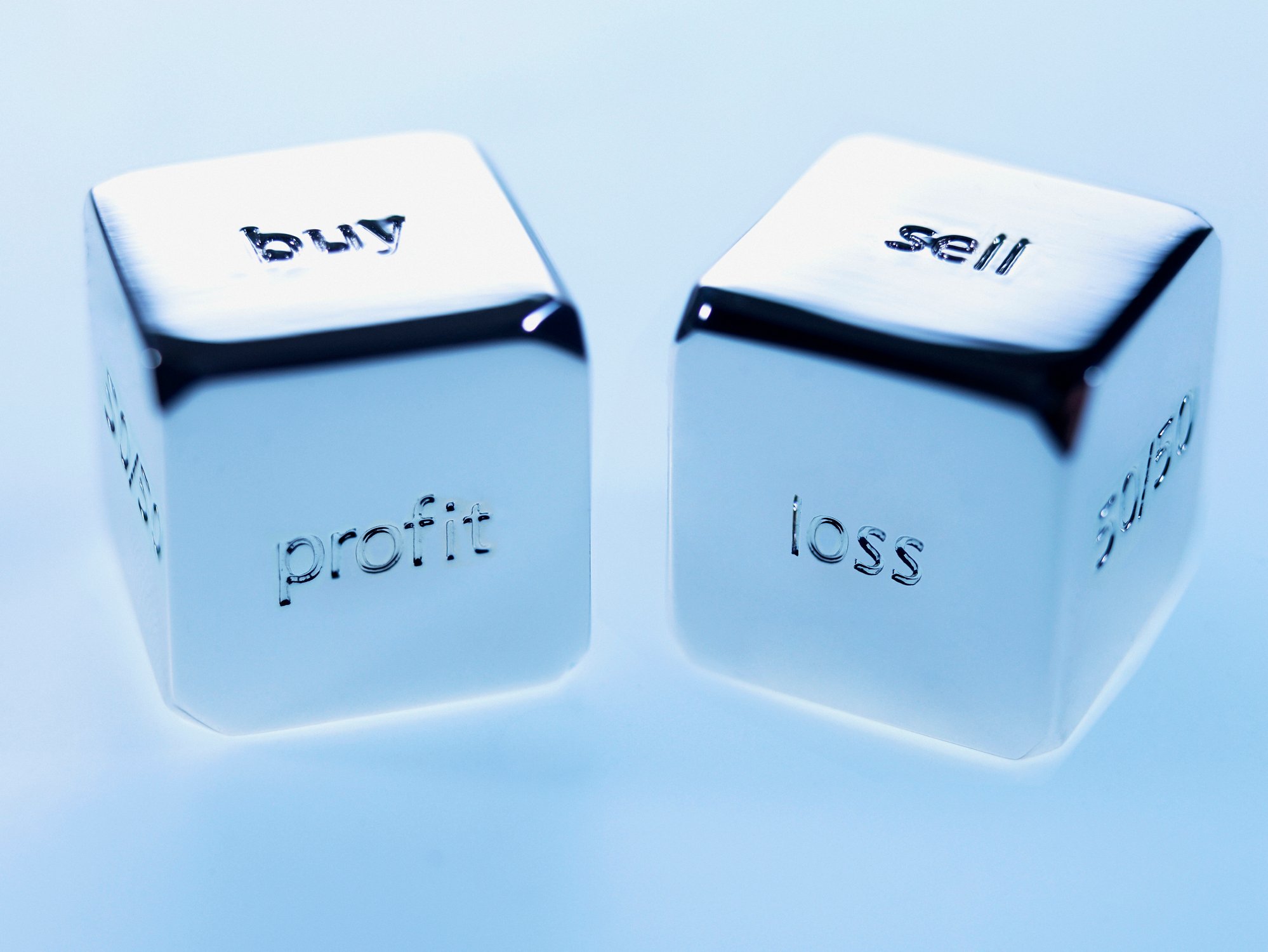 Two silver cubes with buy and profit written on one and sell and loss written on the other.